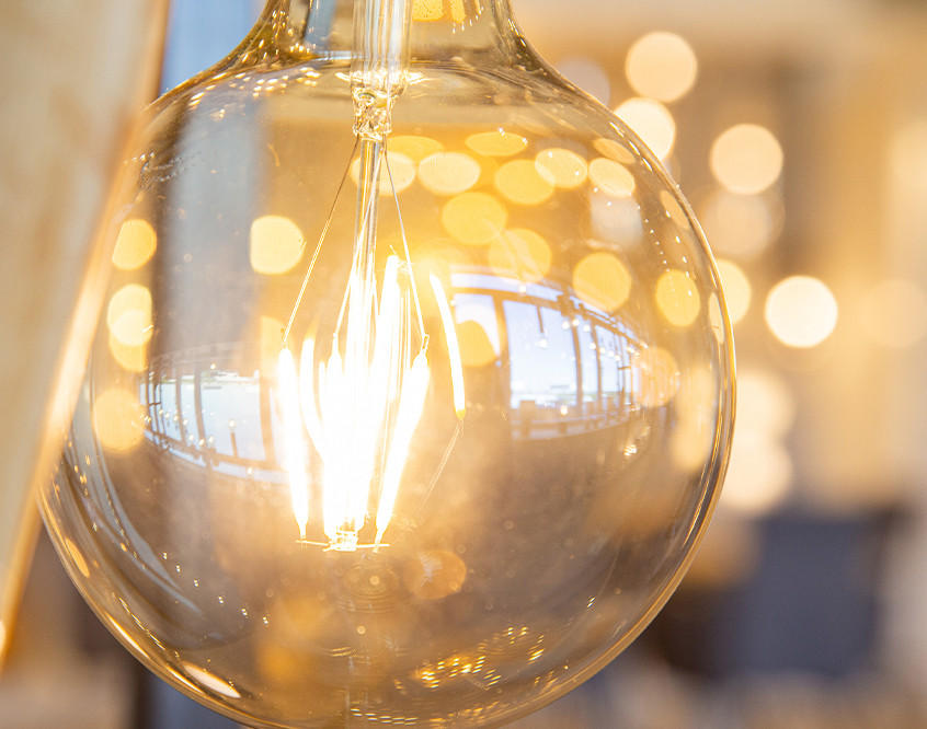 Leuchtende Glühbirne im Close-up mit warmem Bokeh im Hintergrund.