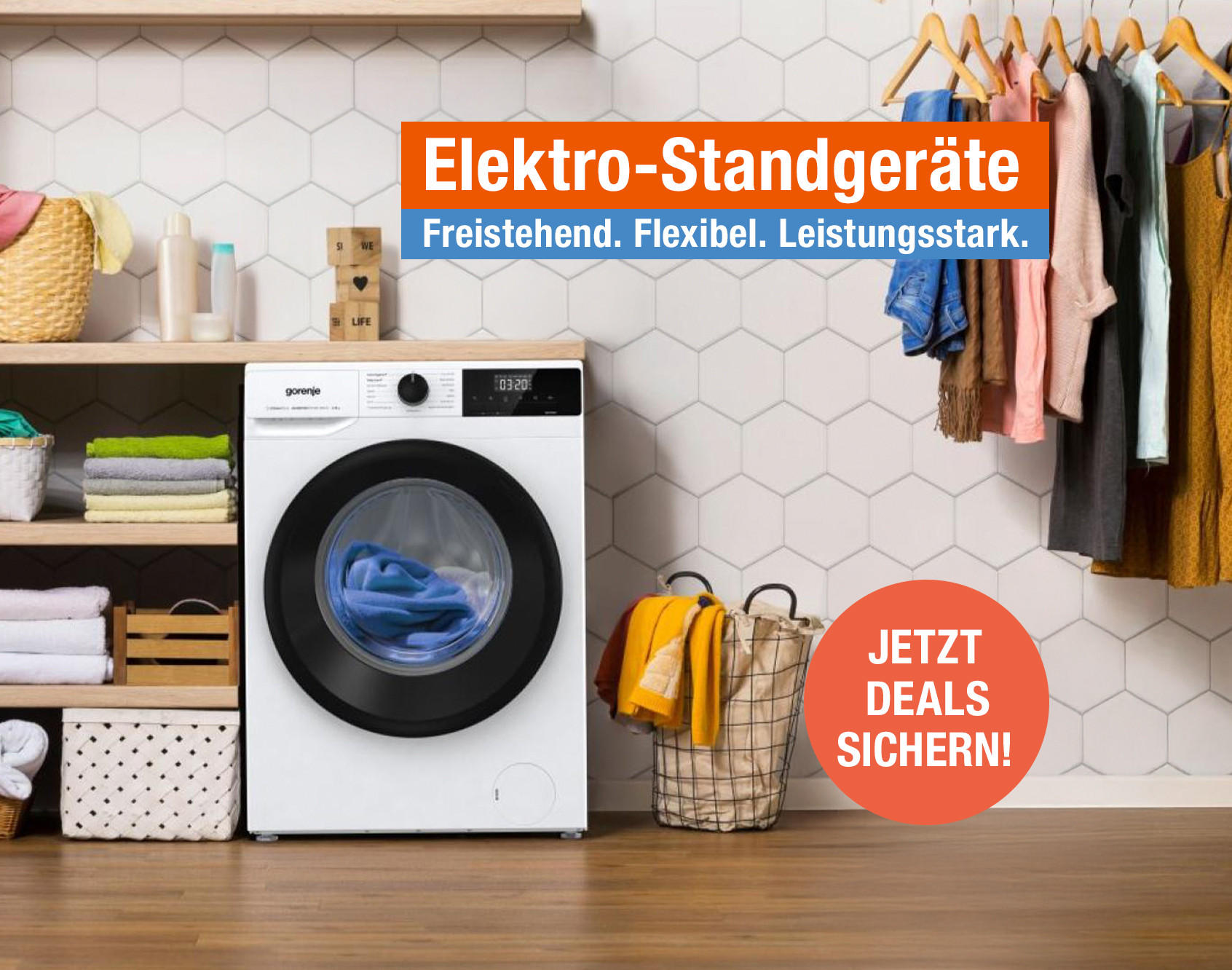 Freistehende weiße Waschmaschine mit blauer Wäsche in der Trommel, daneben Regale mit Handtüchern und Kleidung an einer Kleiderstange, Text 'Elektro-Standgeräte Freistehend. Flexibel. Leistungsstark.' und 'Jetzt Deals sichern!'