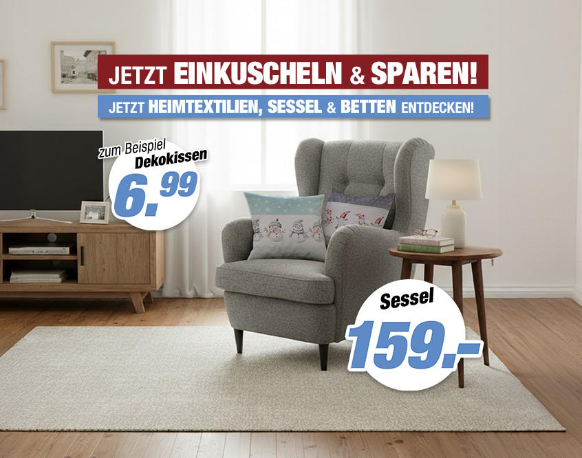 Wohnzimmer mit grauem Ohrensessel, kleinem Holztisch mit Lampe, Fernseher auf Sideboard, Pflanze und Teppich auf Holzboden.