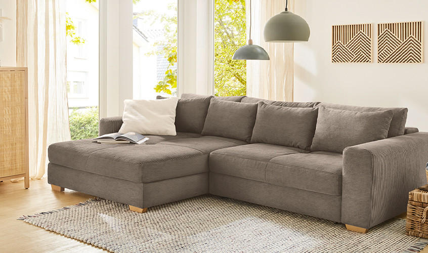 Braunes Cord-Ecksofa im modernen Wohnzimmer, mit Hängelampen, warmen Wandbildern und Körben mit Decke.